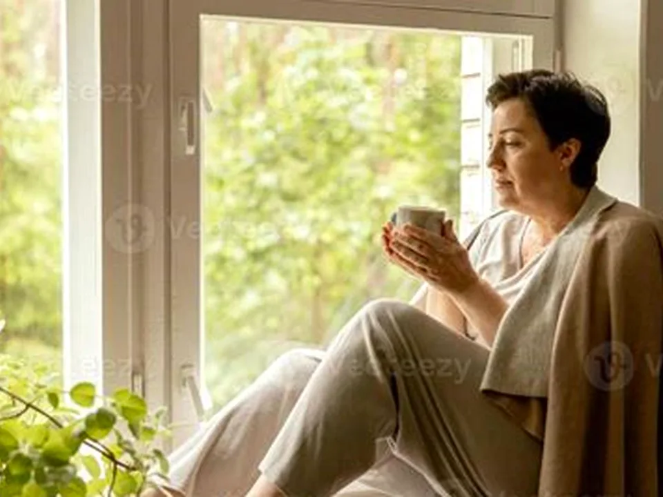 Woman thoughtful at window in soft morning light